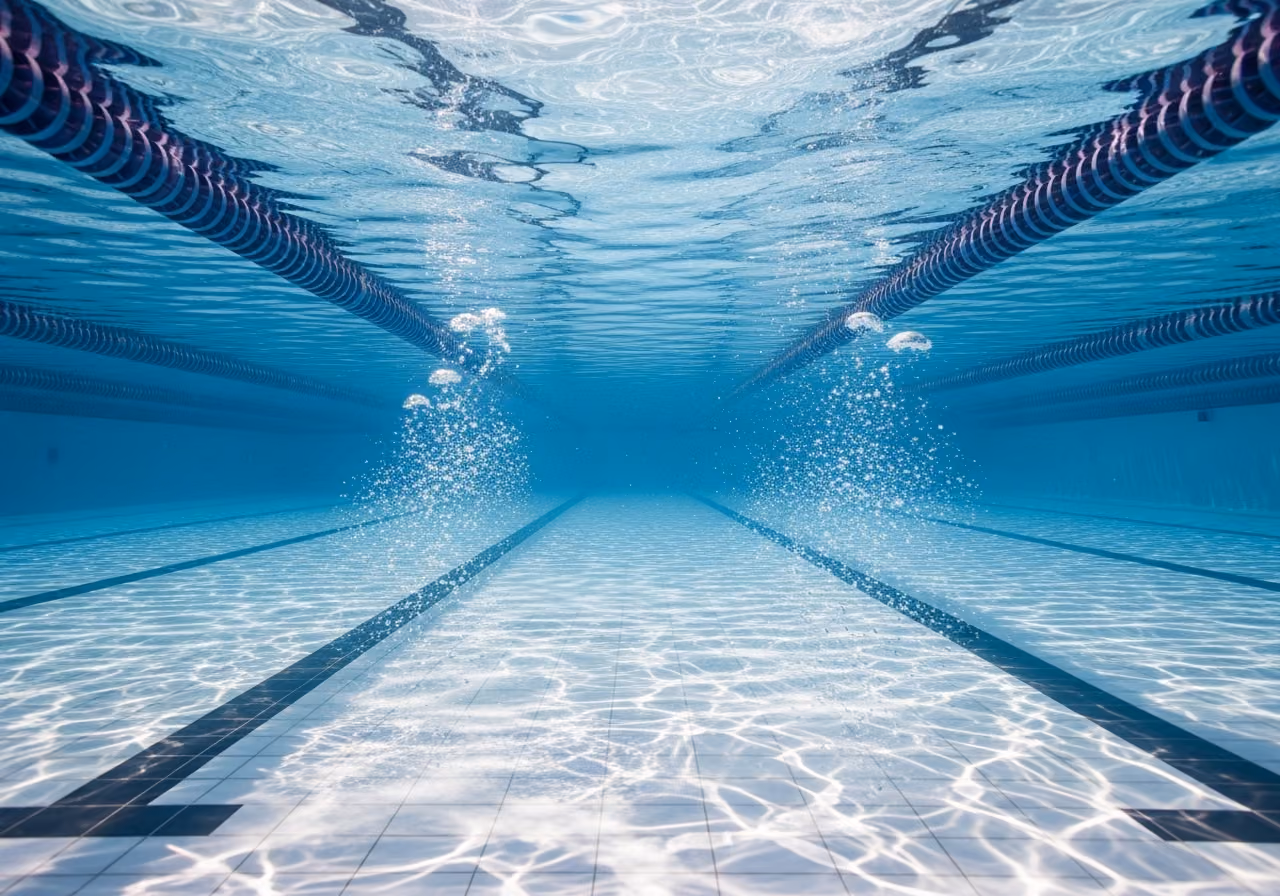 Sanfte Unterwasseransicht einer leeren Schwimmbahn, durch die das Sonnenlicht im Wasser gebrochen wird.
